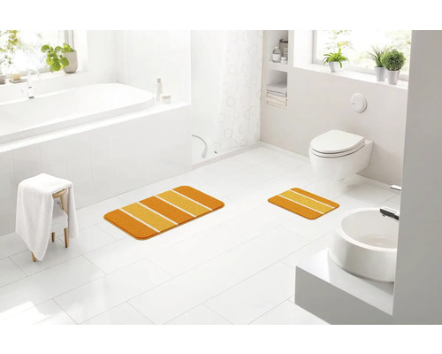 Koupelna s vanou, toaletou, umyvadlem a dvěma koupelnovými předložkami s pruhovaným vzorem