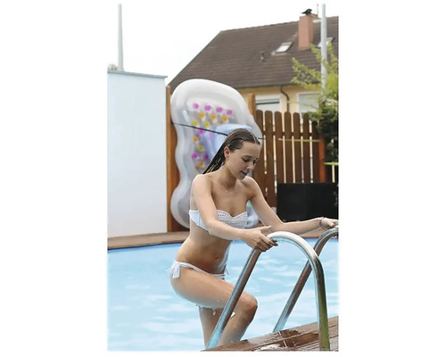 Žena vychází z bazénu po kovovém žebříku. V pozadí je nafukovací vodní podložka.