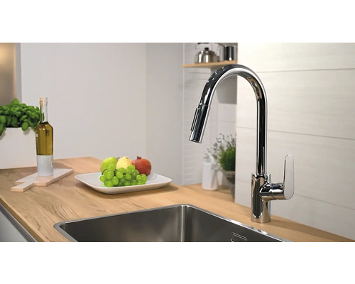 Kuchyňská scéna s umyvadlovou baterií, dřezem a mísou s ovocem na dřevěné pracovní desce