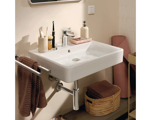 Fotografie koupelny s umyvadlem, baterií, držákem na ručníky a koupelnovými doplňky.