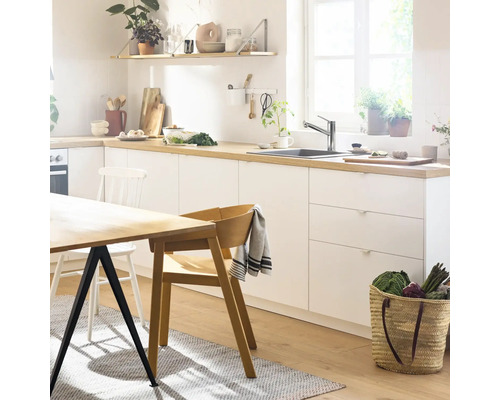 Světlá kuchyně s jídelním stolem, židlemi a kuchyňským náčiním