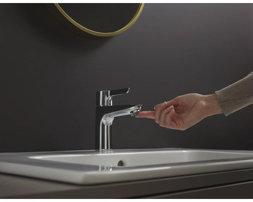 Ruka ovládá kovovou vodovodní baterii na umyvadle.