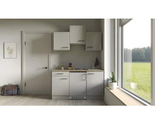 Malá kuchyň s horními skříňkami, dřezem, varnou deskou a chladničkou ve světlé místnosti