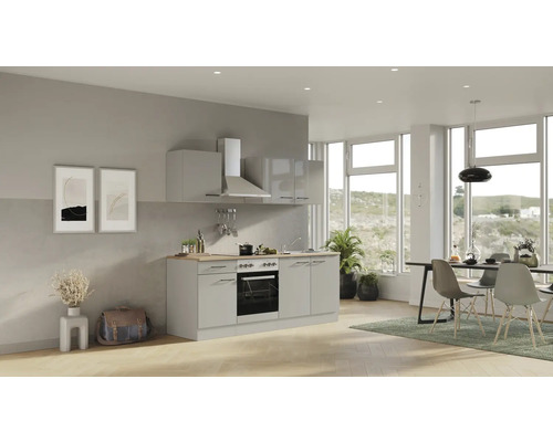 Světlá kuchyně s dřezem, sporákem, digestoří a jídelním stolem v prostorném pokoji s velkými okny