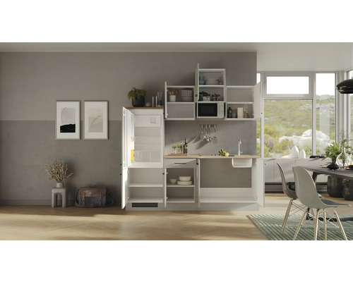 Moderní vestavěná kuchyně s otevřenými skříňkami, mikrovlnnou troubou a lednicí ve světlém pokoji.