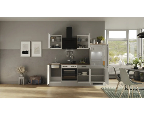 Kompletní vestavěná kuchyně s elektrickými spotřebiči, digestoří a lednicí ve světlé místnosti