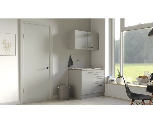 Světlá prádelna s umyvadlem, spodní skříňkou a závěsnou skříňkou pod velkým oknem.