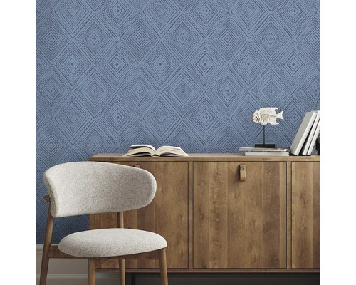 Obývací pokoj s modrými vzorovanými tapetami, dřevěnou komodou a židlí.