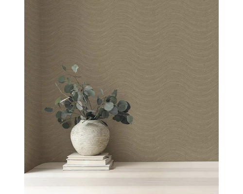 Detail stěny s vlnitou tapetou, s vázou a knihami na stole.