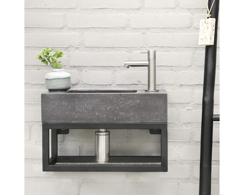 Umyvadlo s betonovou umyvadlovou mísou a kovovým rámem na cihlové zdi