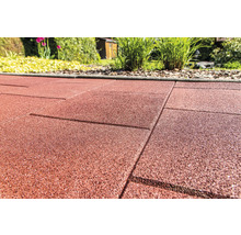 Detail červených gumových terasových desek v zahradě.