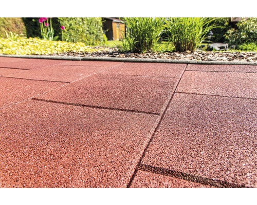 Detail červených gumových terasových desek v zahradě.