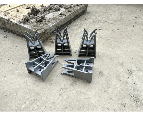 Pět distančních prvků bednění na betonové podlaze