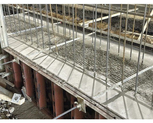 Čerstvě litý beton s výztužnou ocelí v bednění.