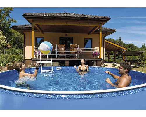 Rodina si hraje s míčem v nadzemním bazénu se žebříkem před domem.