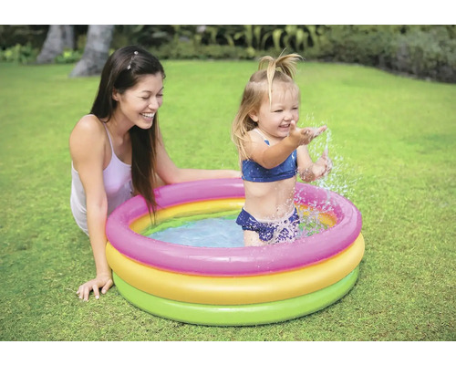 Matka a dítě si hrají v brouzdališti na zahradě.