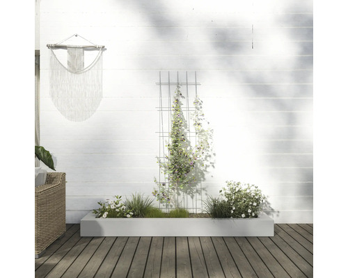 Scéna s truhlíkem, mříží na popínání a nástěnnou dekorací ve venkovním prostoru.