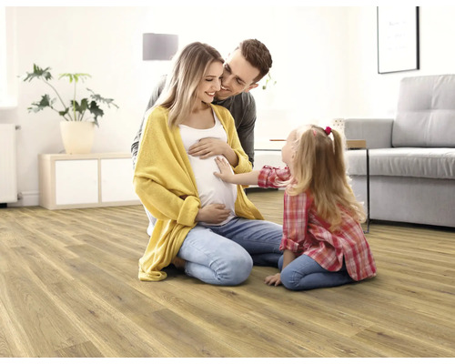 Rodina s dítětem na světlé dřevěné podlaze v obývacím pokoji.