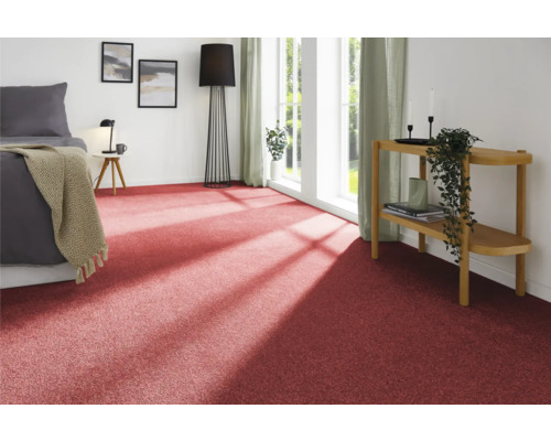 Pohled na pokoj s červeným kobercem, postelí, příručním stolkem a dekorací