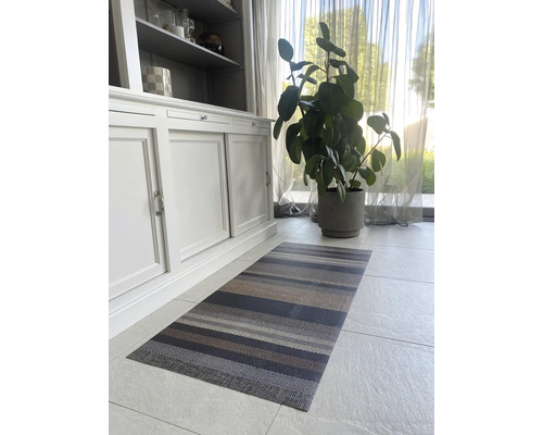 Interiérová fotografie pruhovaného koberce před skříní a pokojovou rostlinou.