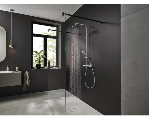 Moderní koupelna se sprchou, umyvadlem a oknem pro světlé a přátelské prostředí.