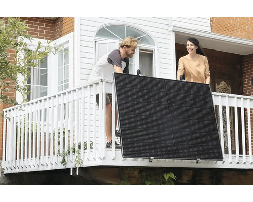 Dva lidé instalují solární panel na balkoně.