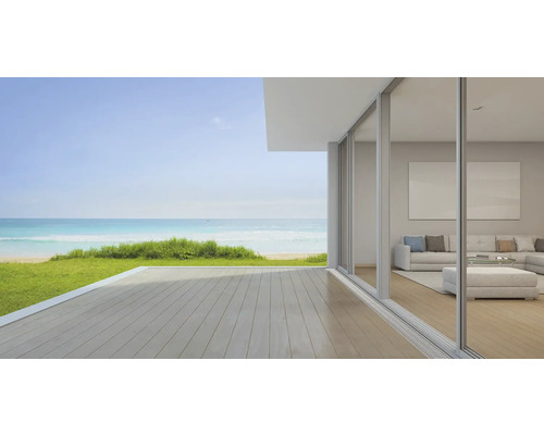 Světlý obývací pokoj s velkými okny a výhledem na moře a pláž.