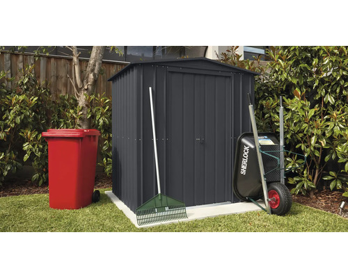 Zahradní scéna s kůlnou na nářadí, popelnicí, kolečkem a hráběmi venku.