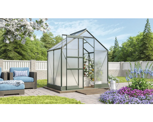 Skleník v zahradě s rostlinami a zahradním nábytkem