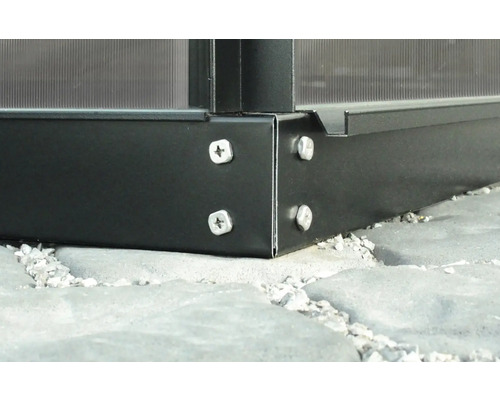 Detail rohu skleníku se šrouby na kamenné dlaždice