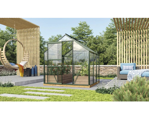 Skleník v zahradě s rostlinami a zahradní dekorací