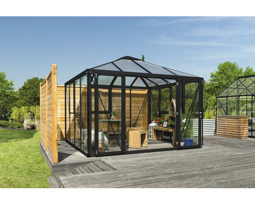 Skleník se skleněnými stěnami a dřevěným interiérem na zahradě.