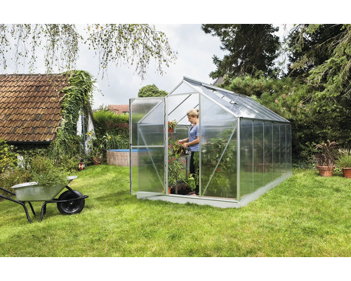 Skleník v zahradě se ženou a rostlinami
