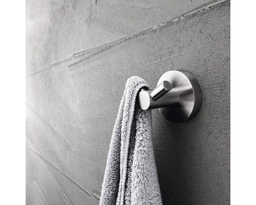 Kovový věšák na ručníky s ručníkem na šedé zdi