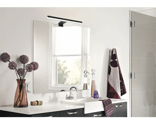 Moderní koupelna s umyvadlem, zrcadlem, lampou a dekoracemi.