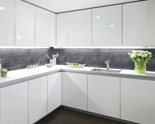 Světlá kuchyně s bílými skříňkami, umyvadlem a pracovní deskou