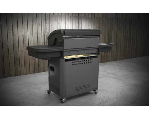 Tmavě šedý gril na kolečkách s bočními policemi a kolečky před dřevěnou stěnou