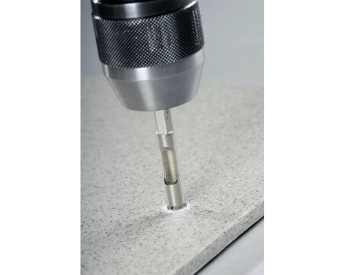 Detailní záběr vrtačky vrtající otvor do dlaždice