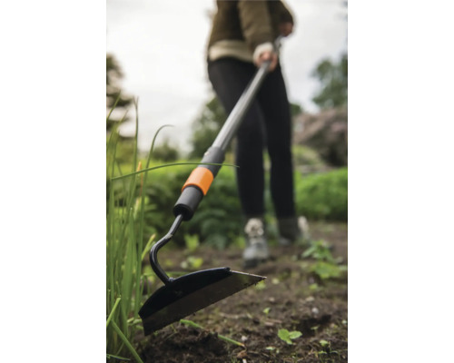 Zahradní motyka s teleskopickou násadou používaná na zahradě.