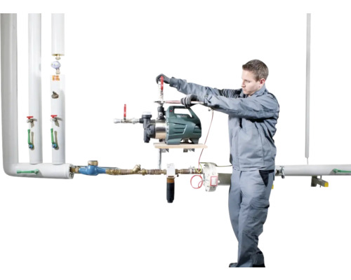 Instalatér montuje zahradní čerpadlo na potrubní systém.