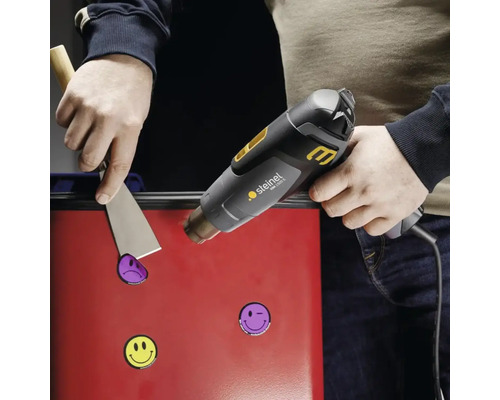 Použití horkovzdušné pistole k odstranění samolepek z povrchu pomocí špachtle