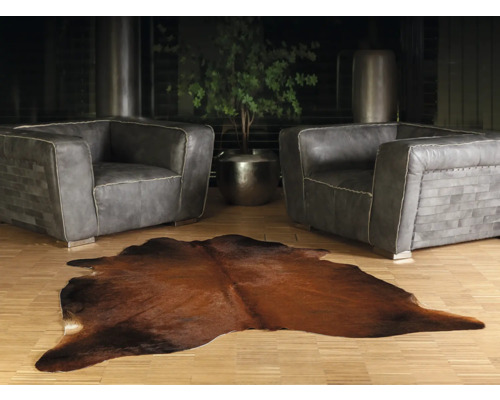 Obývací pokoj se dvěma šedými koženými křesly a hnědým kobercem z kravské kůže