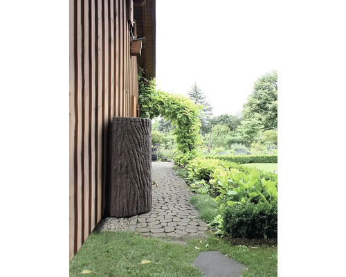 Zahrada s dešťovým sudem vypadajícím jako kmen stromu vedle domu