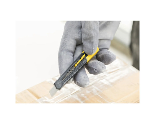 Ruka v rukavici řeže pásku na kartonové krabici nožem