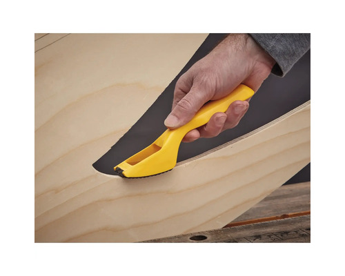 Ruka s žlutým odjehlovacím nástrojem na hraně dřeva