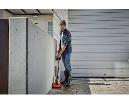 Muž čistí betonovou stěnu elektrickým kartáčem venku