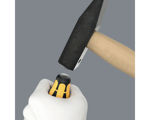 Ruka drží chránič palce pod kladivem