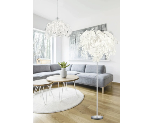 Obývací pokoj s šedou pohovkou, kulatými stoly a listovými svítidly jako stropní svítidlo a stojací lampa.