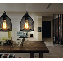 Dvě černé závěsné lampy s pletěným stínidlem nad jídelním stolem.