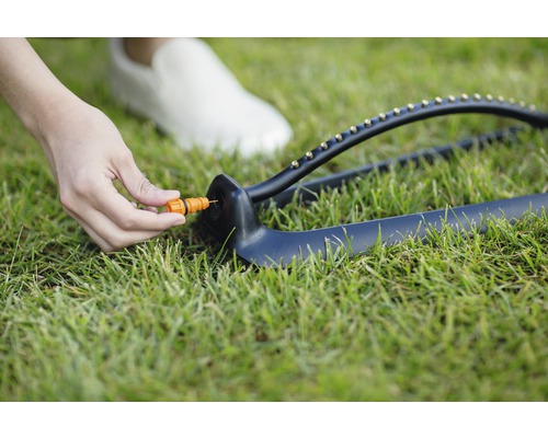 Zavlažovač trávníku s regulačním kusem na trávníku